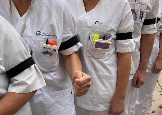 Bildet viser sykepleiere i uniform med sorte sørgebånd.