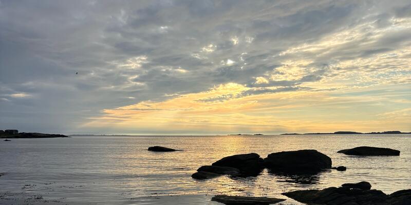 Strand, himmel og sol gjennom sky