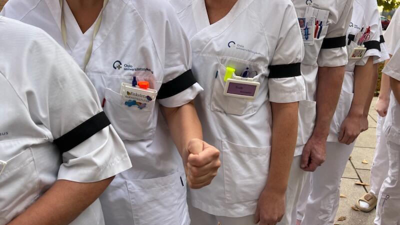 Bildet viser sykepleiere i uniform med sorte sørgebånd.