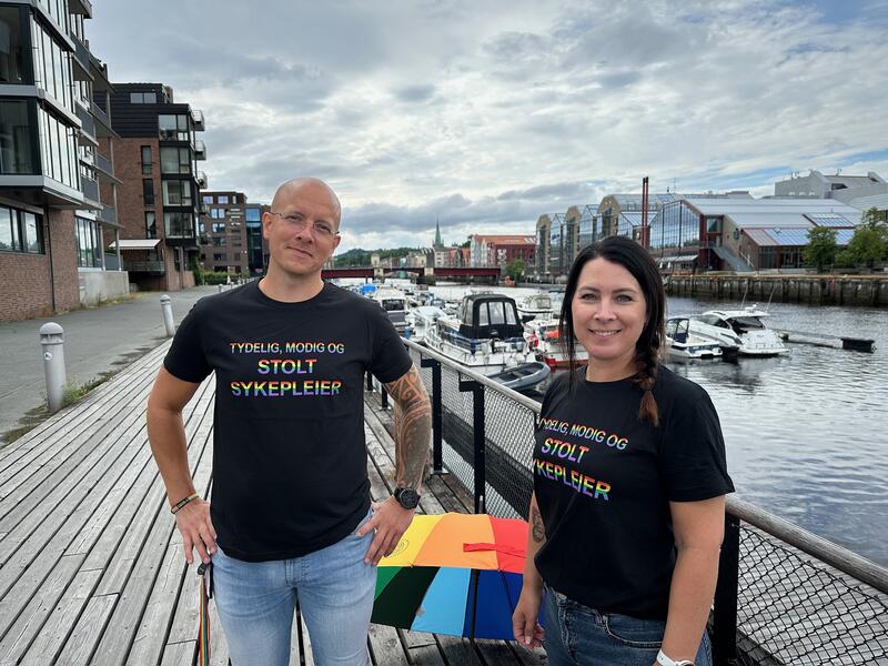 Fylkesleder i Trøndelag Kenneth Sandmo Grip og fylkesnestleder Randi Wågheim i sorte t-skjorter med regnbuefarget tekst "tydelig, modig stolt sykepleier"